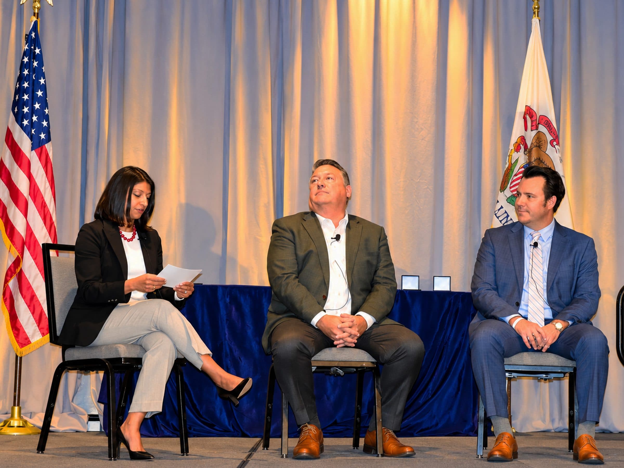 Three panelists seated on stage during the luncheon's panel discussion.