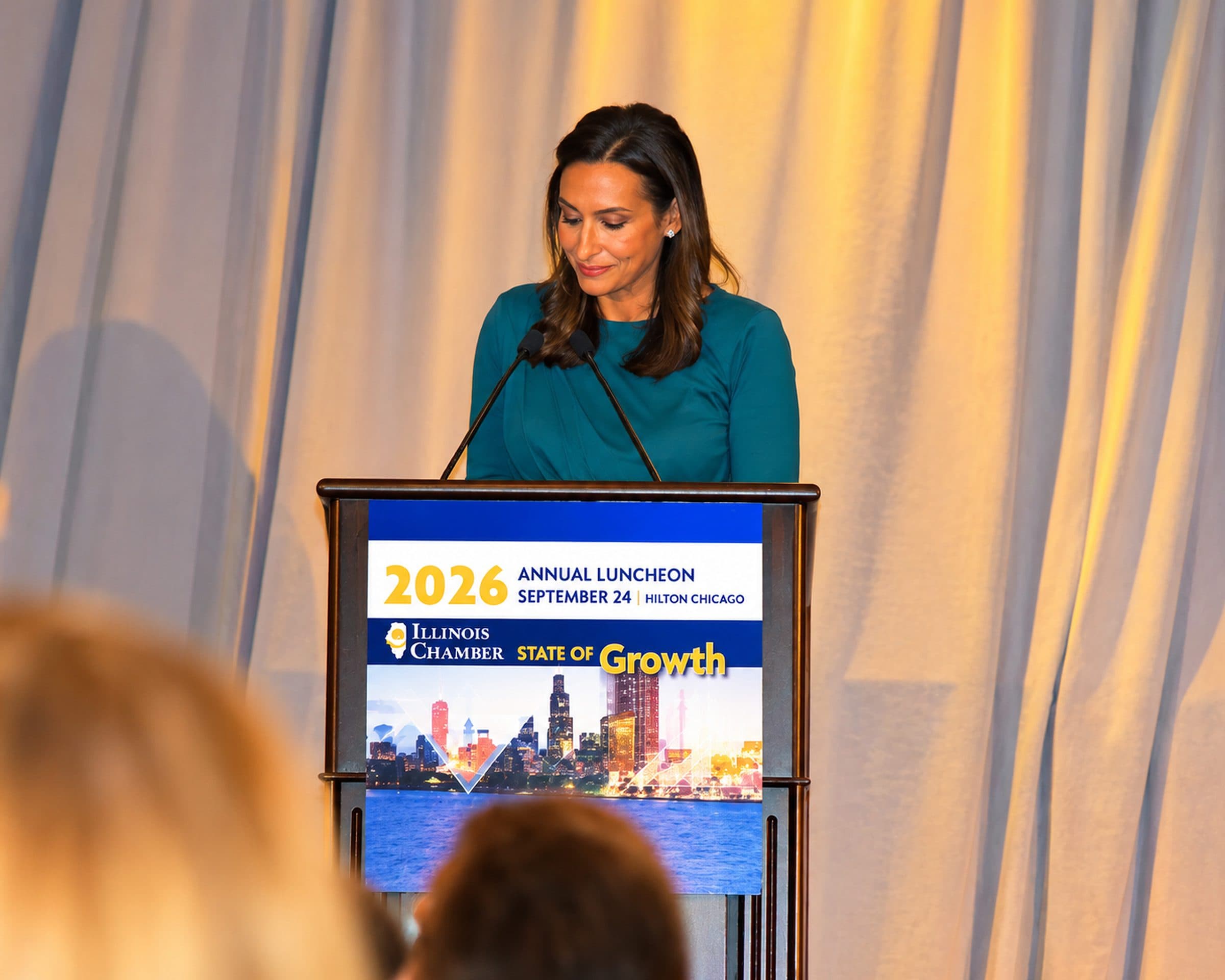 A woman addresses the audience from the podium.