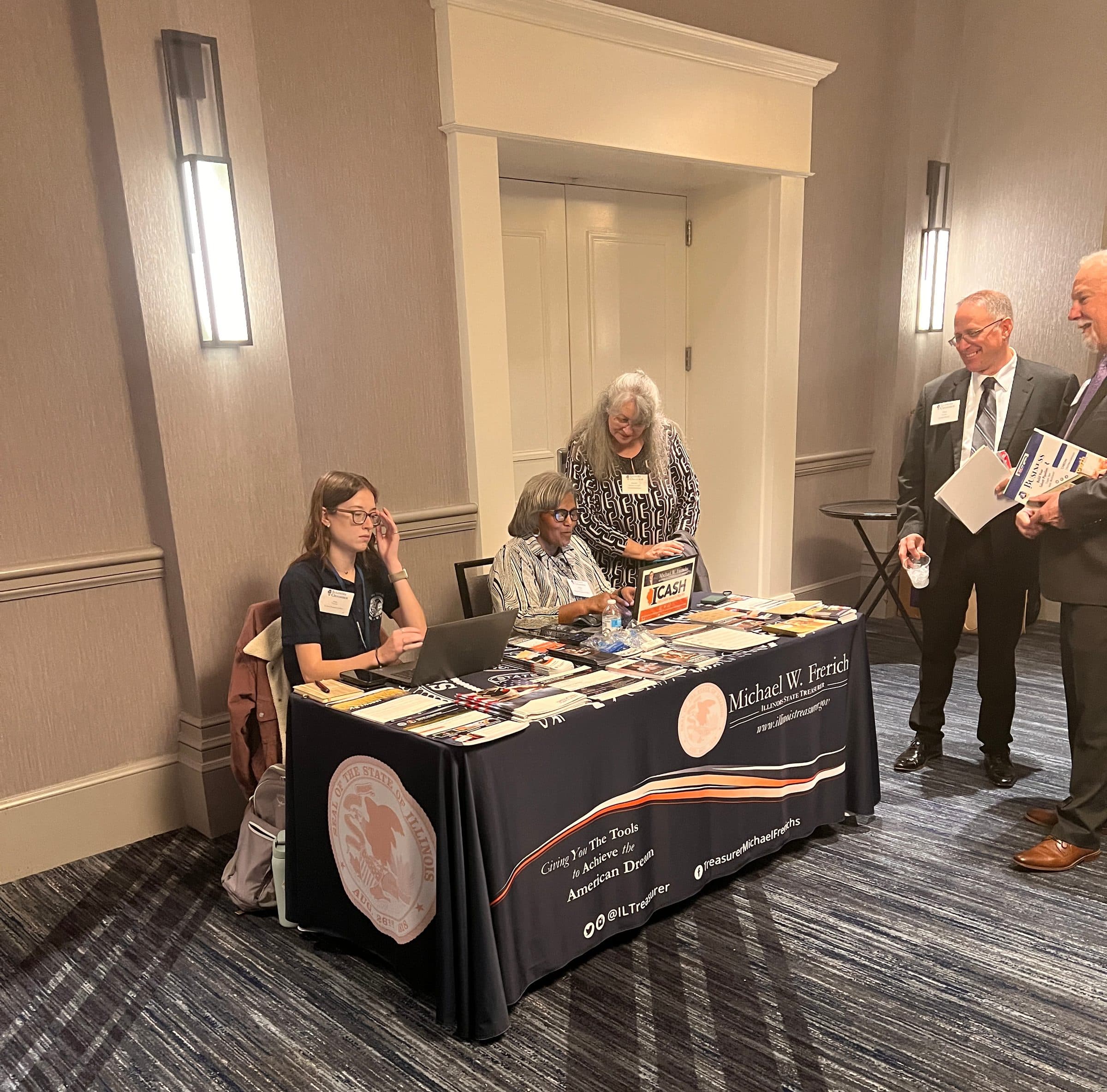 Attendees visit the Illinois State Treasurer's exhibit table in the expo.