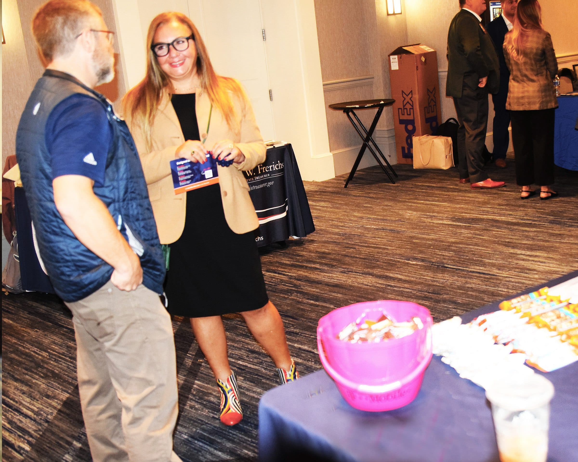 Two guests talk beside an exhibitor table in the expo.