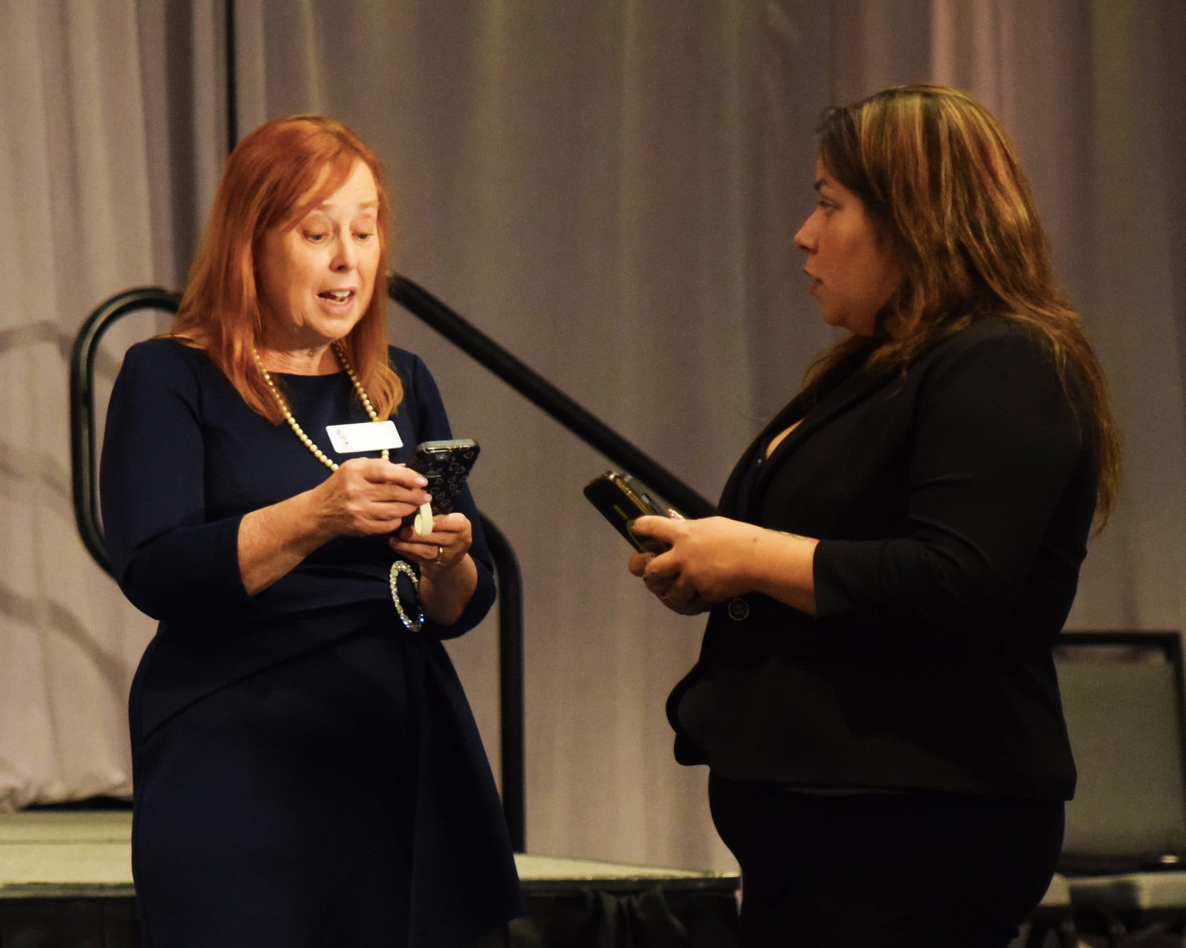 Two women talk near the stage before the program.