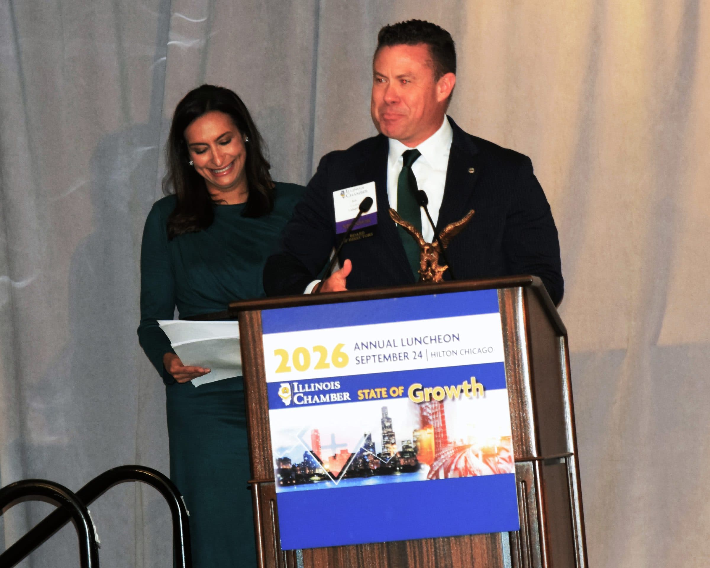 An award recipient at the podium holding an eagle statuette.