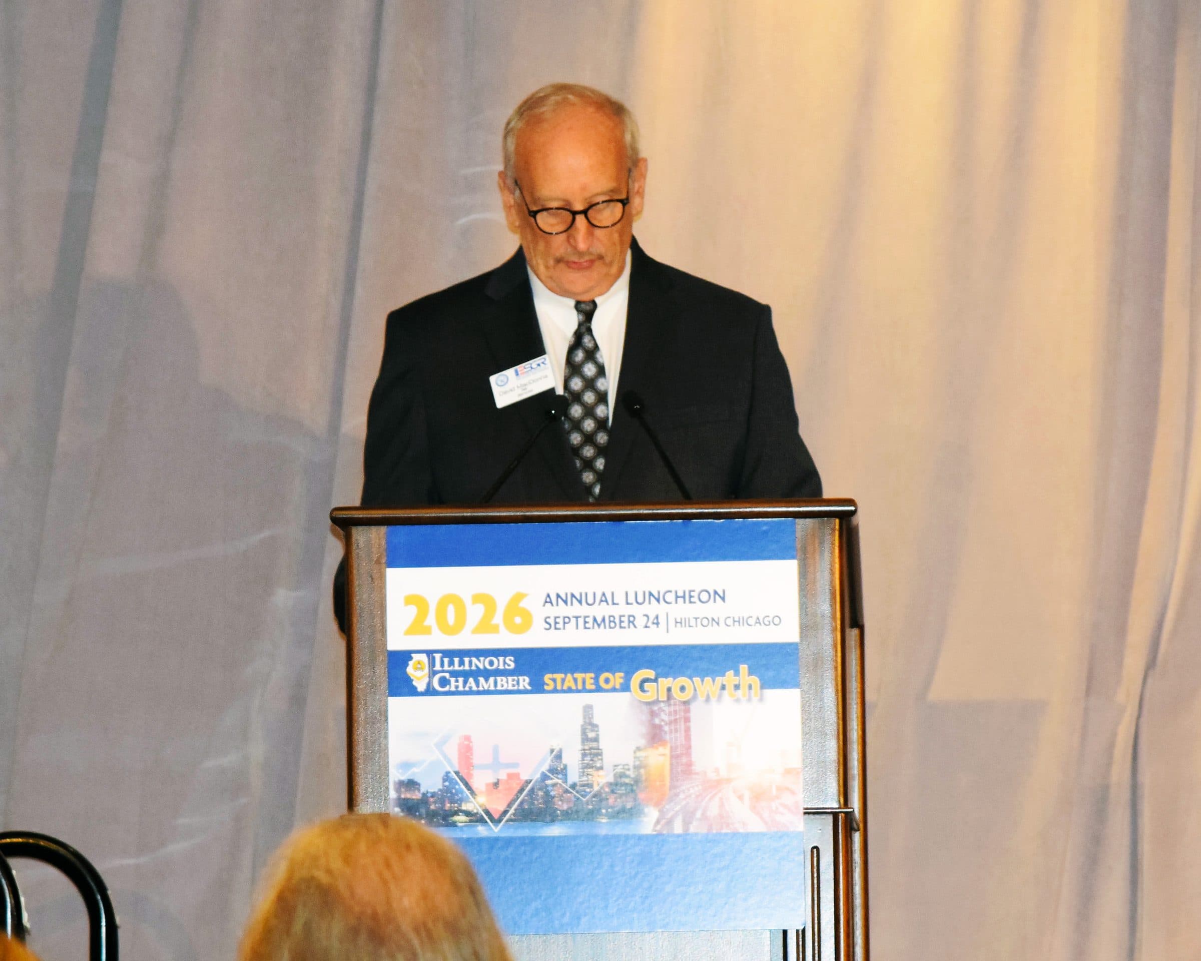 A speaker in glasses addresses the luncheon.
