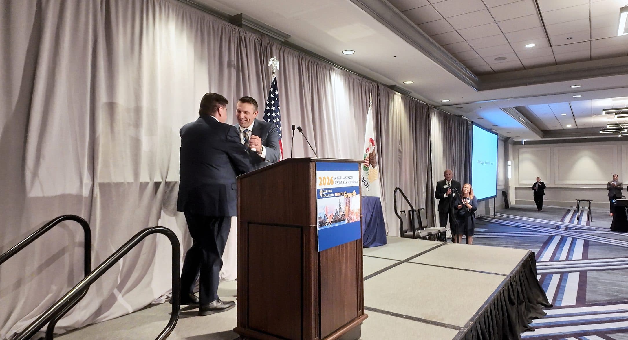 A speaker is greeted at the podium.