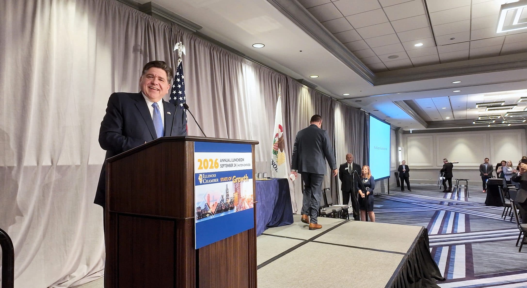 A speaker smiles from the podium during his remarks.