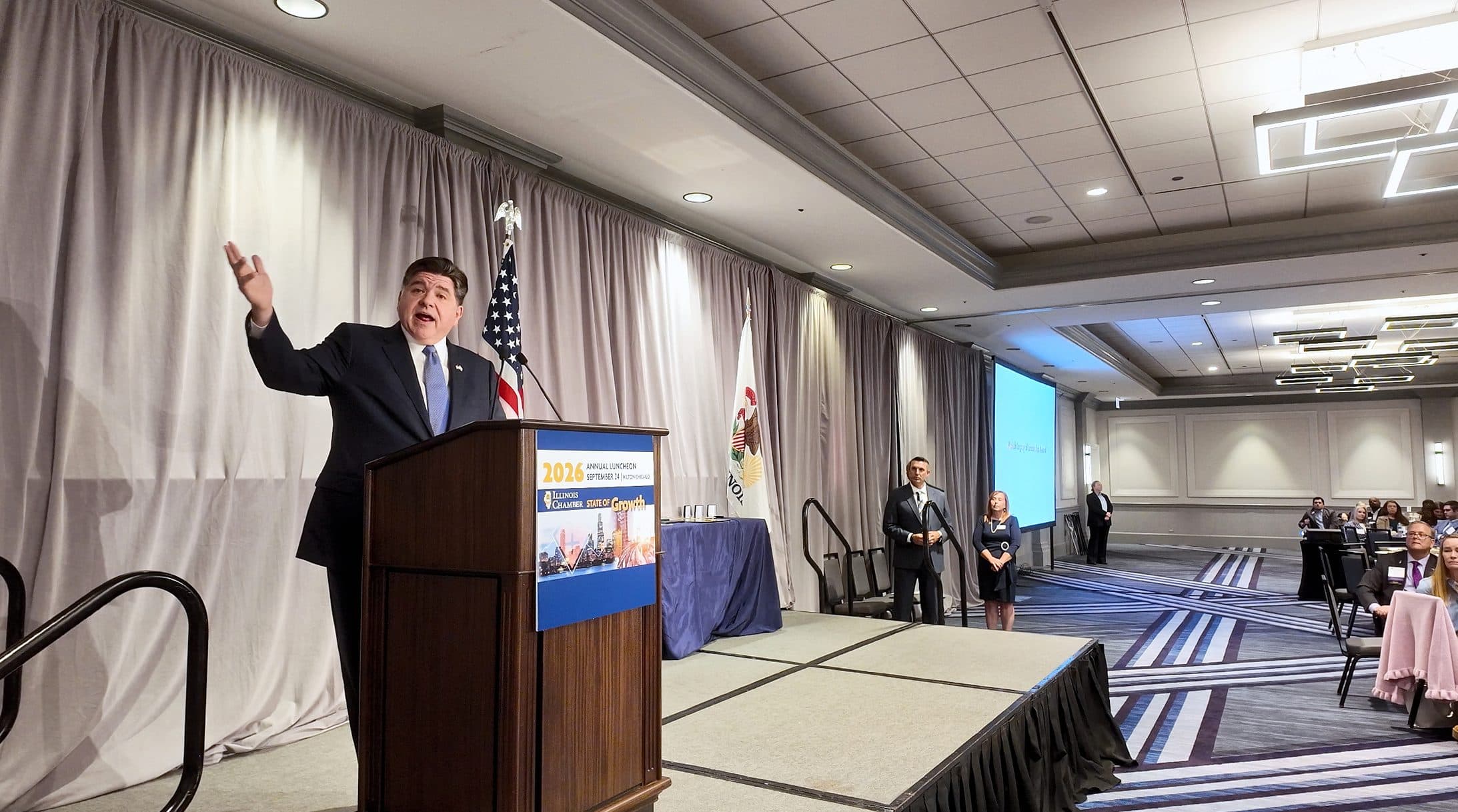 A speaker raises his arm while addressing the ballroom.